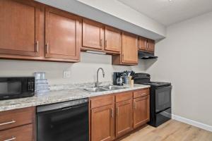 a kitchen with wooden cabinets and a black dishwasher at Newly Renovated Unit in Central Spfld #103 in Springfield