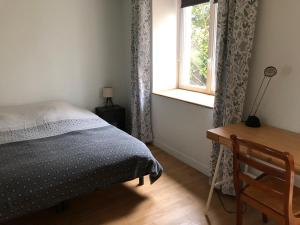 a bedroom with a bed and a desk and a window at Gîte entre l'océan et le golfe in Surzur