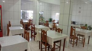 a dining room with white tables and chairs in a restaurant at Hotel João Luzia in Villa Nova de Resende