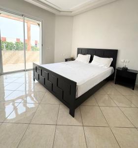 a bedroom with a large bed and a large window at Cozy Seaside Villa in Bir Jedíd Saint-Hubert