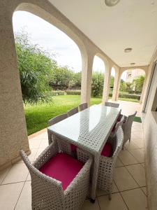a patio with a table and chairs on a porch at Cozy Seaside Villa in Bir Jedíd Saint-Hubert
