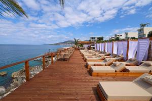 a row of lounge chairs on a pier next to the ocean at Palmera Dream Vila in Sarandë
