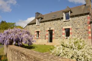 a stone house with a flowering tree in front of it at Du rocher in Plélo