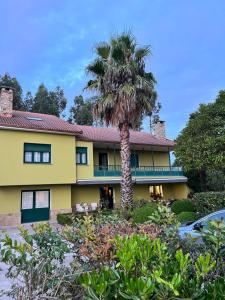 a palm tree in front of a yellow building at Hostal Finca La Oliva in Oleiros