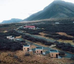 eine Gruppe von Häusern auf einem Feld mit einem Berg in der Unterkunft Hotel Hafnarfjall in Borgarnes