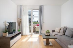 a living room with a couch and a tv at Sunny resort apartment with pool access in Zadar