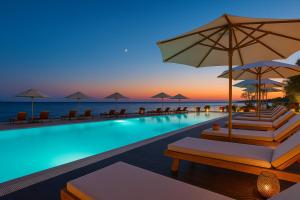 a pool with chairs and umbrellas and the ocean at Sunny resort apartment with pool access in Zadar