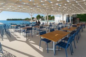 a patio with tables and chairs and the water at Sunny resort apartment with pool access in Zadar