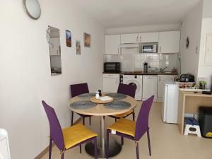 a kitchen with a table and purple chairs in a kitchen at Cami del Canigou in Vernet-les-Bains