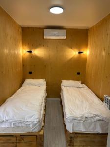 two beds in a room with wooden walls at Пан0рама in Saty