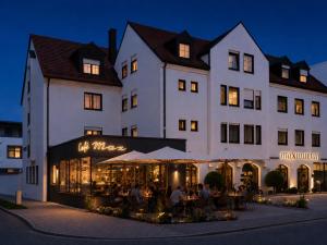 a large white building with a restaurant in front of it at Hotel Garni Maximilian in Dingolfing