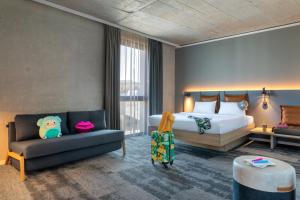 a hotel room with a bed and a couch at Moxy Outletcity Metzingen in Metzingen