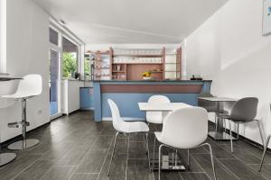 a room with tables and white chairs and a kitchen at Villa Manuela in Opatija