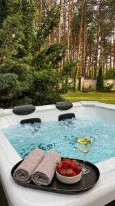 a hot tub with a bowl of strawberries and a drink at Golden Villas Luxury Garden Retreat - Jacuzzi & Sauna in Konstancin-Jeziorna