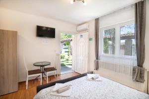 a bedroom with a bed and a window and a table at Guesthouse Kristina in Palić
