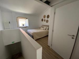 a small white bedroom with a bed and a window at Tomarhousing Heritage in Tomar