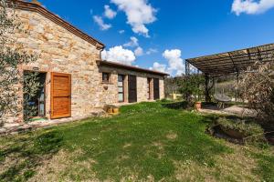 an exterior view of a stone house with a yard at Agriturismo Scannano in Serre di Rapolano
