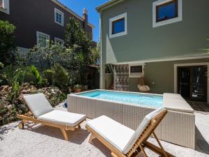 a backyard with a swimming pool and two chairs and a house at Villa Ada in Faro