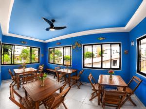 a dining room with blue walls and wooden tables and chairs at Pousada Jardim Mágico in Ponta Negra