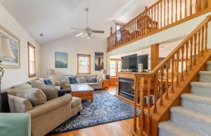 a living room with a staircase and a couch at Carotank Clubhouse - Corolla Village, 200 Yds to Beach, Foosball, Pool, Hot Tub, Flex Stays in Corolla