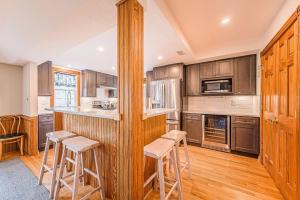a kitchen with wooden cabinets and bar stools at Carotank Clubhouse - Corolla Village, 200 Yds to Beach, Foosball, Pool, Hot Tub, Flex Stays in Corolla +68 photos