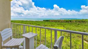 a balcony with two white chairs and the ocean at Sunrise Penthouse 3316 Ocean Pointe 1BR 2BA in Tavernier