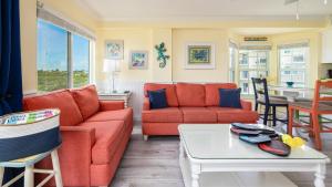 a living room with orange couches and a table at Sunrise Penthouse 3316 Ocean Pointe 1BR 2BA in Tavernier