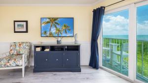 a living room with a tv and a balcony at Sunrise Penthouse 3316 Ocean Pointe 1BR 2BA in Tavernier