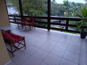 a porch with red chairs and a view of trees at Casa indaial in Indaial +8 photos
