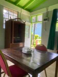 a wooden table in a room with chairs and a television at Anthurium Apartment in Roseau
