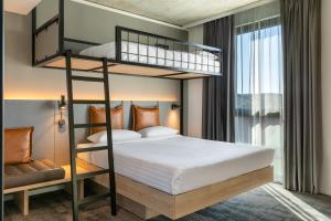 a bedroom with two bunk beds and a window at Moxy Wuerzburg in Würzburg