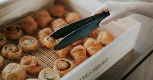 a person holding a knife in a box of pastries at Nesthotel Alt Meguro Ekimae in Tokyo