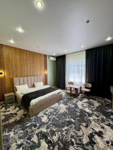 a bedroom with a large bed and a large rug at Essenali in Taraz