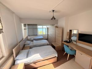 a room with two beds and a desk and a television at Divisey Pansiyon in Unye