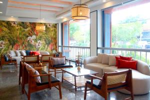 a living room with couches and tables and windows at Coco Beach Hotel Jomtien Pattaya in Jomtien Beach