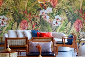 a living room with a white couch with a tropical wallpaper at Coco Beach Hotel Jomtien Pattaya in Jomtien Beach