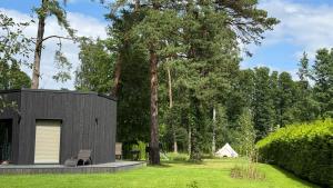 a small black house in the middle of a yard at Beautiful Tinyhouse near the Beach in Lapmežciems