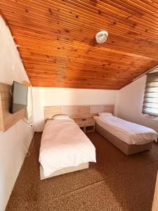 a bedroom with two beds and a wooden ceiling at Divisey Pansiyon in Unye +3 photos