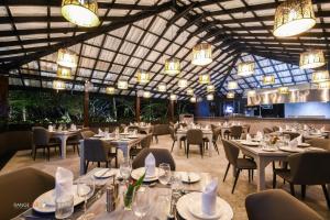 a dining room with tables and chairs and chandeliers at Madu River Reach in Balapitiya