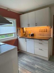 a kitchen with white cabinets and a sink and a window at Svolvær Minihouse in Kongsmarka