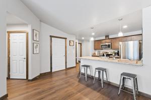 a kitchen with white walls and wooden floors and bar stools at Destiny Cove in Kalispell