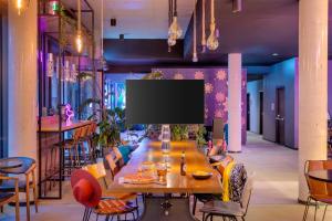 a dining room with a long table and a flat screen tv at Moxy Hamburg Altona in Hamburg