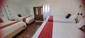 a white room with two beds and a window at Pukari Hotel Cusco in Cusco