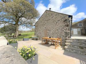 a patio with a wooden table in front of a stone building at 1 Bed in Carnforth oc-90554 in Middleton