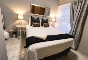 a bedroom with a bed with black pillows and a window at Zhantique Guest House 2- Unit 11 in Boksburg