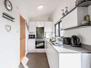 a white kitchen with white cabinets and a clock at 1 Bed in Weymouth oc-82099 in Osmington +6 photos