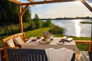 a picnic table with food and a view of a lake at Ezermāja "Spārītes" in Geraņimova