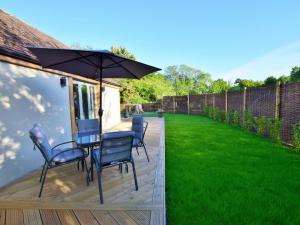 a deck with a table and chairs and an umbrella at 1 Bed in Lymington oc-50723 in Sway