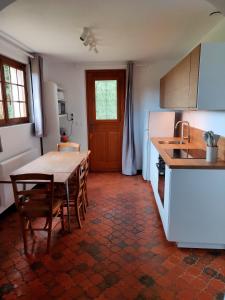 a kitchen with a table and chairs and a refrigerator at Au cerisier in Saint-Maulvis
