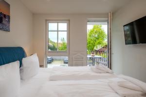 a white bedroom with a bed and a balcony at Strandhaus Zingst Apartment 11 in Zingst